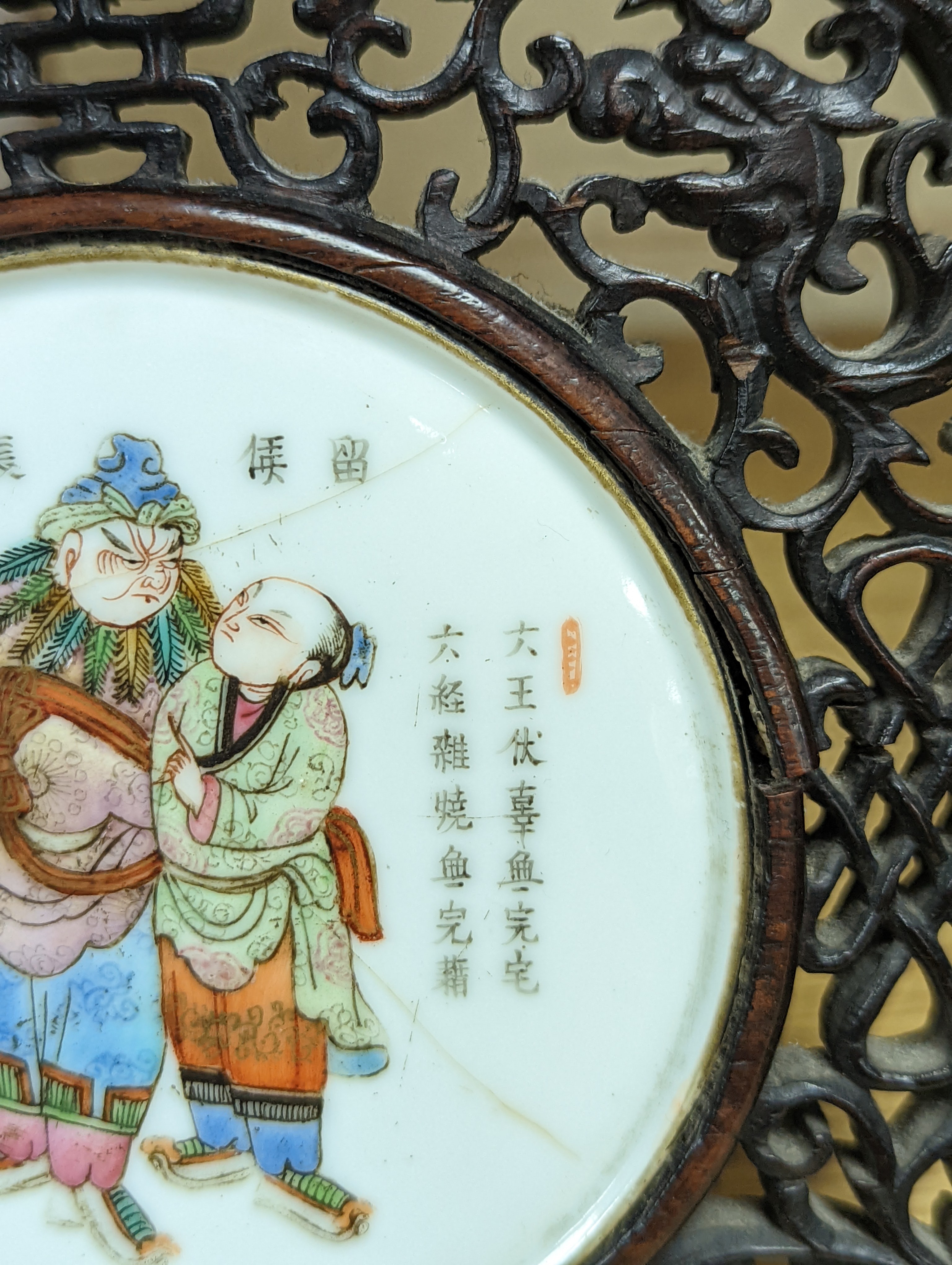 A 19th century Chinese famille rose circular plaque or cover, inset into a wood surround, cracks 15cm sq